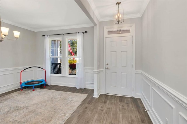 foyer entrance with a notable chandelier, dark hardwood / wood-style floors, and ornamental molding