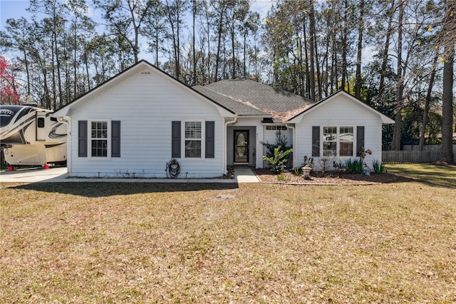 ranch-style home with roof with shingles, a front yard, and fence