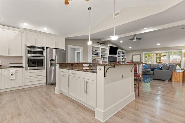 636 Old Plantation Rd, Jekyll Island, GA 31527 - kitchen with stainless steel appliances, vaulted ceiling, ceiling fan, open floor plan, and a breakfast bar area