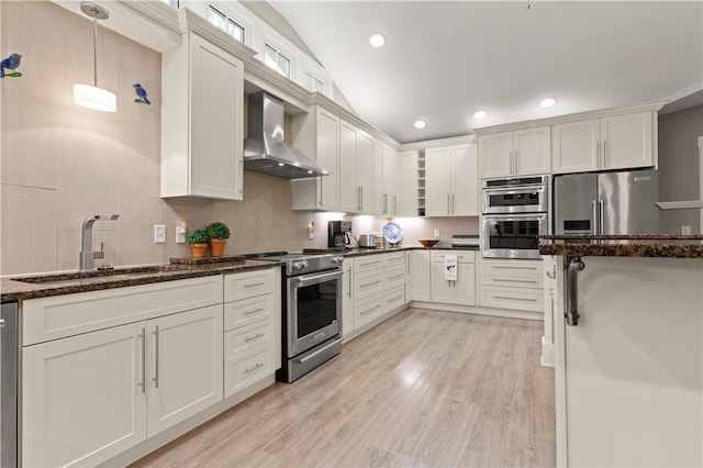 636 Old Plantation Rd, Jekyll Island, GA 31527 - kitchen featuring wall chimney range hood, stainless steel appliances, a sink, light wood-style flooring, and dark stone countertops