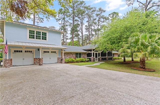 636 Old Plantation Rd, Jekyll Island, GA 31527 - view of front of home featuring an attached garage, asphalt driveway, a sunroom, brick siding, and metal roof