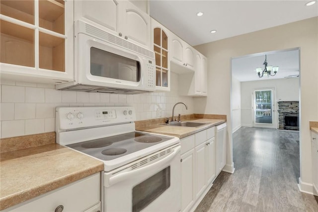 kitchen with sink, hanging light fixtures, light hardwood / wood-style floors, white appliances, and white cabinets