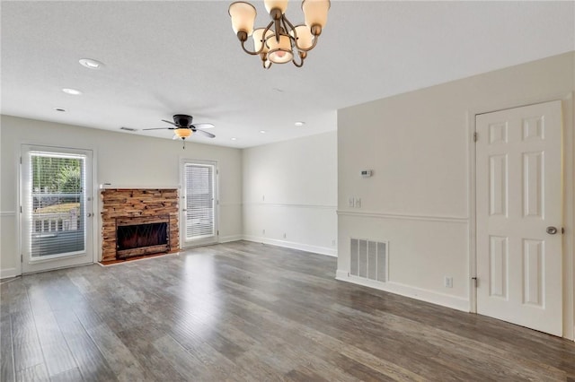 unfurnished living room with a fireplace, ceiling fan with notable chandelier, and dark wood-type flooring