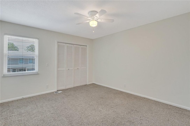 unfurnished bedroom with ceiling fan, a closet, and carpet floors