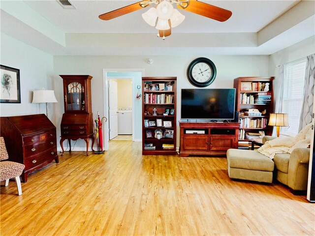 2300 Albany Ave, Waycross, GA 31503 - living room featuring ceiling fan, light wood-type flooring, washer / clothes dryer, and a raised ceiling