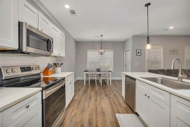 63 Greyfield Dr, Brunswick, GA 31525 - kitchen with appliances with stainless steel finishes, a sink, wood finished floors, tasteful backsplash, and white cabinets