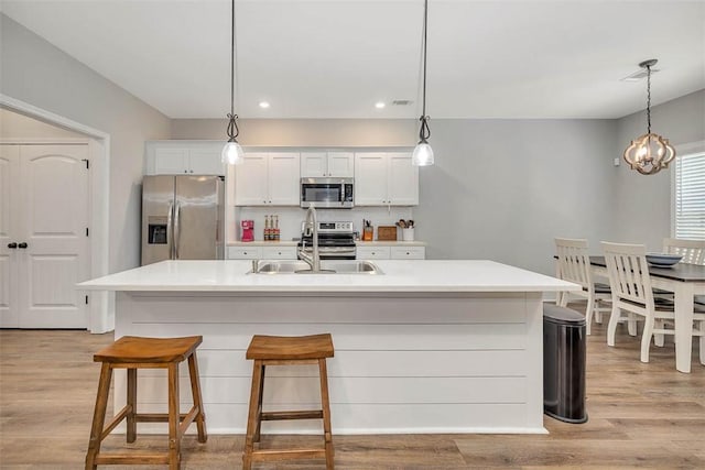63 Greyfield Dr, Brunswick, GA 31525 - kitchen featuring appliances with stainless steel finishes, light wood-style floors, white cabinetry, a kitchen bar, and recessed lighting
