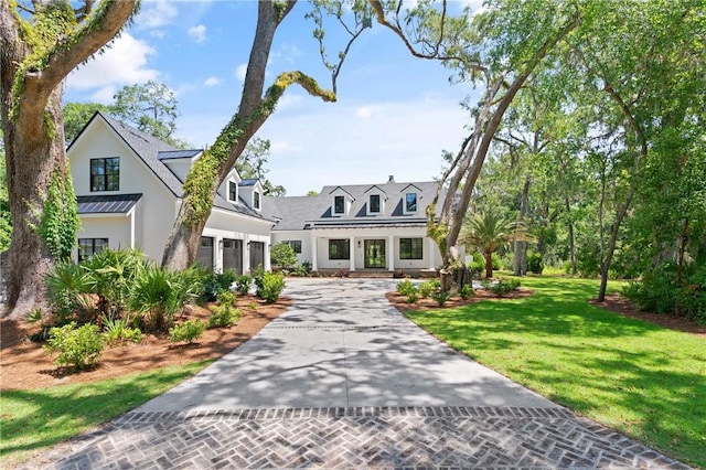 104 Point Ln, Saint Simons Island, GA 31522 - view of front of home featuring driveway, an attached garage, a front yard, stucco siding, and a standing seam roof