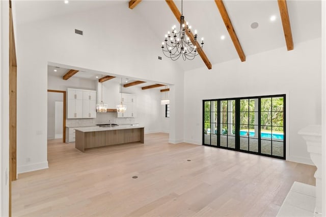 104 Point Ln, Saint Simons Island, GA 31522 - living room with beamed ceiling, high vaulted ceiling, a chandelier, plenty of natural light, and light wood-type flooring
