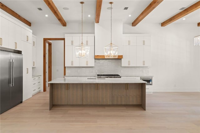 104 Point Ln, Saint Simons Island, GA 31522 - kitchen with stainless steel built in refrigerator, a chandelier, decorative backsplash, light wood-style flooring, and a large island with sink