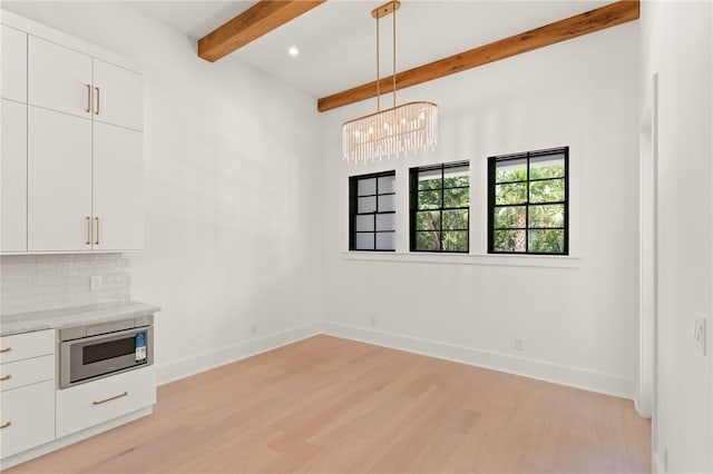 104 Point Ln, Saint Simons Island, GA 31522 - unfurnished dining area featuring beam ceiling, light wood finished floors, and a chandelier