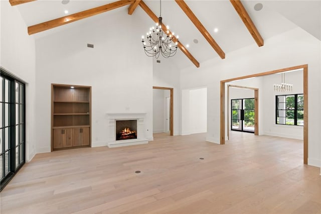 104 Point Ln, Saint Simons Island, GA 31522 - unfurnished living room featuring a chandelier, high vaulted ceiling, beamed ceiling, light wood-style flooring, and a lit fireplace