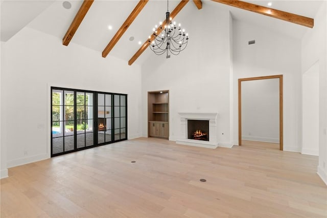 104 Point Ln, Saint Simons Island, GA 31522 - unfurnished living room with high vaulted ceiling, a chandelier, beam ceiling, light wood-style floors, and a lit fireplace