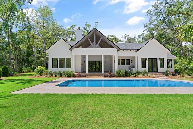 104 Point Ln, Saint Simons Island, GA 31522 - back of property featuring french doors, a chimney, an outdoor pool, stucco siding, and a lawn