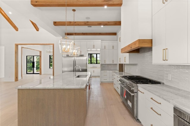 104 Point Ln, Saint Simons Island, GA 31522 - kitchen featuring premium appliances, light wood finished floors, backsplash, a large island with sink, and beam ceiling