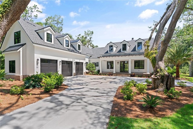 104 Point Ln, Saint Simons Island, GA 31522 - modern farmhouse style home with driveway, stucco siding, a standing seam roof, a metal roof, and a garage