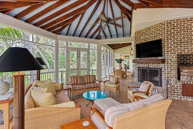 sunroom / solarium with vaulted ceiling with beams, ceiling fan, and a fireplace