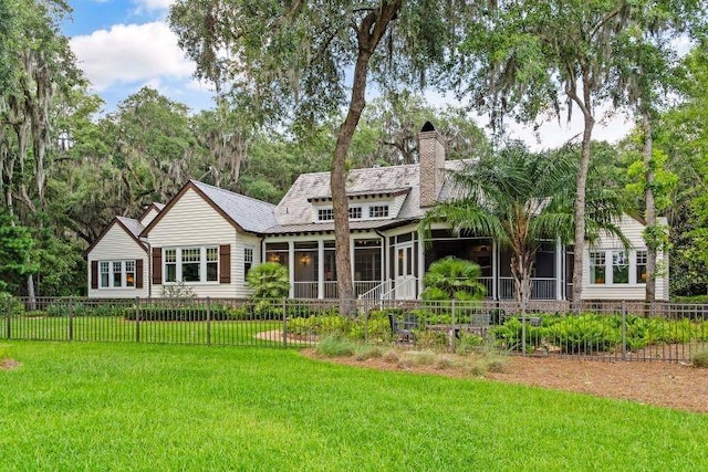 back of house featuring a lawn and a sunroom