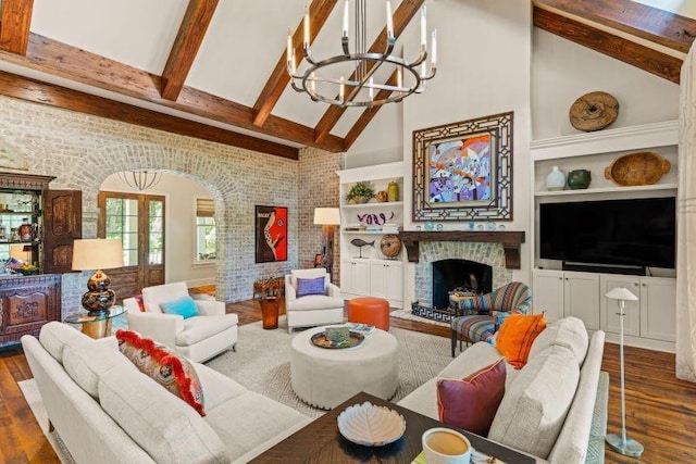 living room featuring dark hardwood / wood-style floors, high vaulted ceiling, a notable chandelier, and brick wall