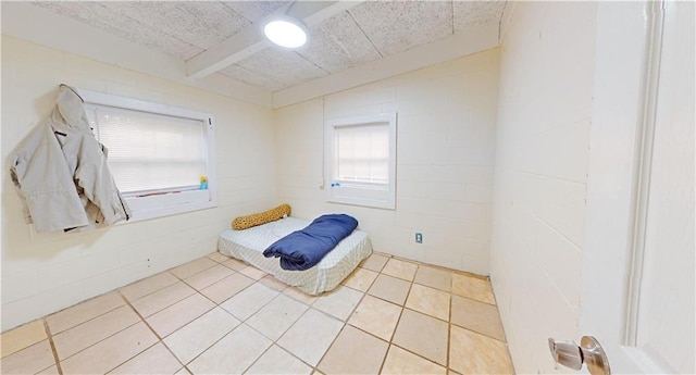 tiled bedroom featuring beamed ceiling