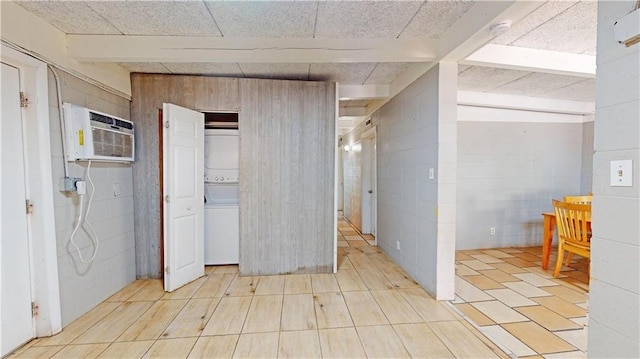 interior space with beam ceiling, an AC wall unit, and a drop ceiling