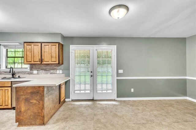 122 Tyson Ln, Allenhurst, GA 31301 - kitchen with french doors, light countertops, decorative backsplash, brown cabinetry, and a peninsula