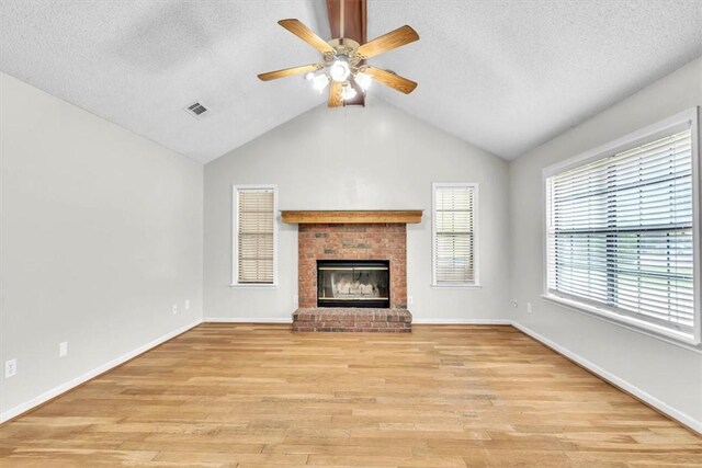 122 Tyson Ln, Allenhurst, GA 31301 - unfurnished living room featuring a textured ceiling, ceiling fan, light wood-type flooring, a fireplace, and vaulted ceiling