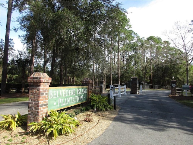 1186 Winterberry Ct NE, Townsend, GA 31331 - community / neighborhood sign featuring a gate and view of scattered trees