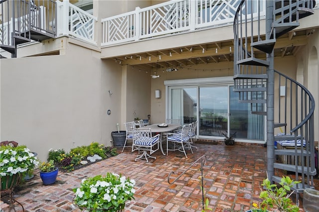 view of patio with stairway, outdoor dining space, and a balcony
