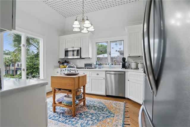 kitchen featuring stainless steel appliances, light countertops, white cabinetry, light wood-type flooring, and a chandelier
