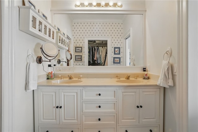 bathroom featuring double vanity, crown molding, and a spacious closet