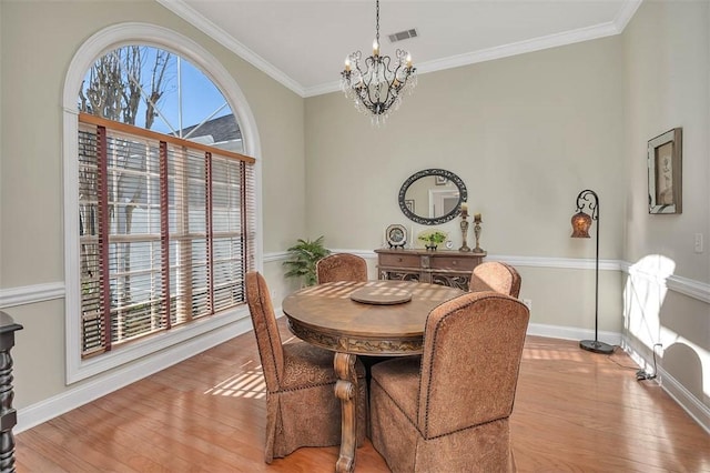 dining area with crown molding, plenty of natural light, light hardwood / wood-style floors, and a notable chandelier