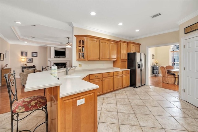 kitchen with ceiling fan, sink, a kitchen breakfast bar, stainless steel refrigerator with ice dispenser, and kitchen peninsula