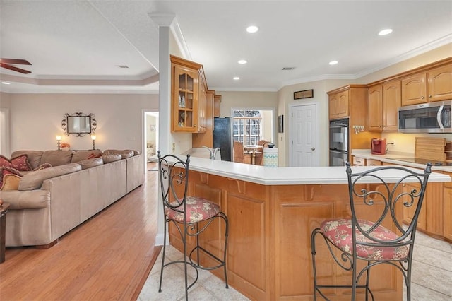 kitchen featuring black appliances, kitchen peninsula, a breakfast bar area, and ornamental molding