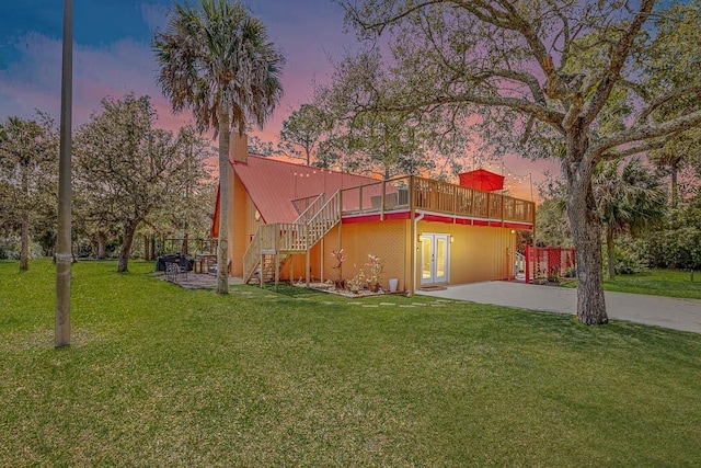 view of front of property featuring french doors, a yard, a patio, and a deck