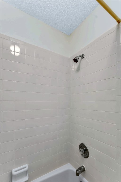 full bathroom featuring washtub / shower combination and a textured ceiling