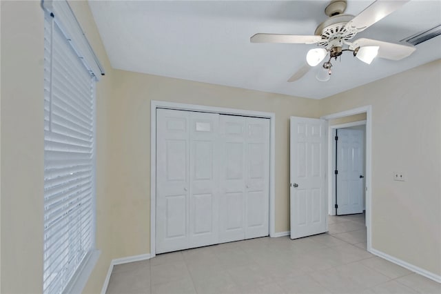 unfurnished bedroom featuring a closet, light tile patterned flooring, ceiling fan, and baseboards