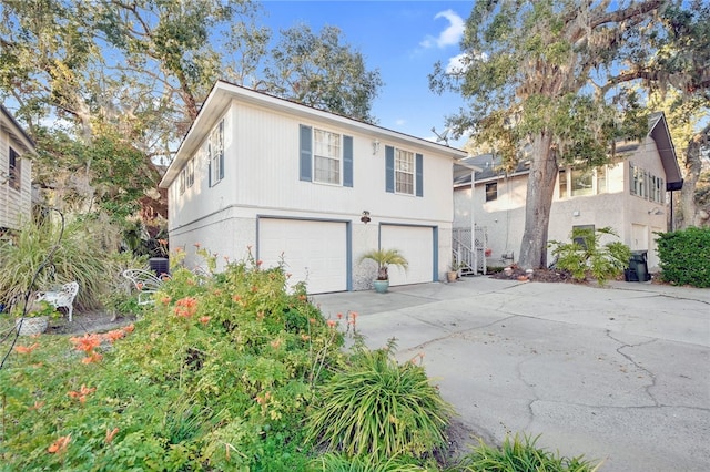 exterior space with concrete driveway, central AC unit, and an attached garage