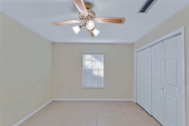 unfurnished bedroom featuring light tile patterned floors, a closet, visible vents, ceiling fan, and baseboards