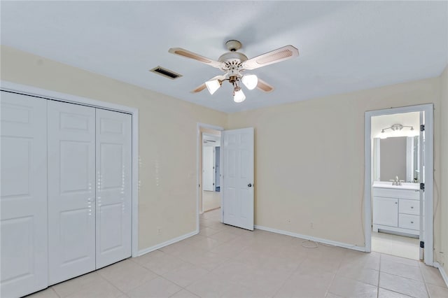 unfurnished bedroom with light tile patterned flooring, sink, ensuite bath, a closet, and ceiling fan