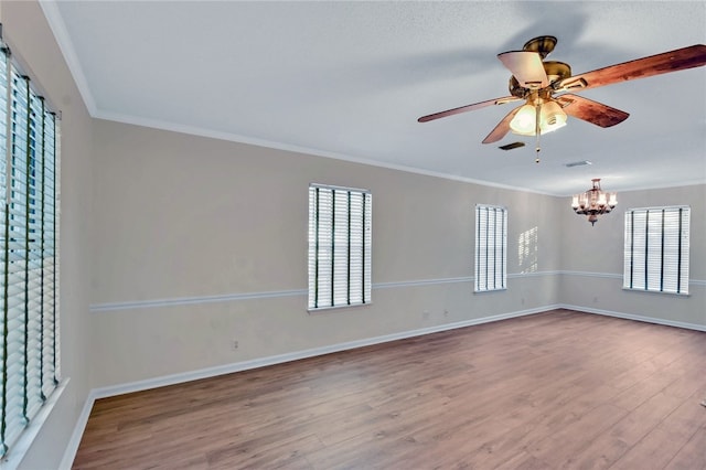 empty room with hardwood / wood-style flooring, ceiling fan with notable chandelier, and ornamental molding