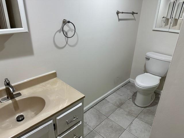 bathroom with toilet, vanity, baseboards, and tile patterned floors