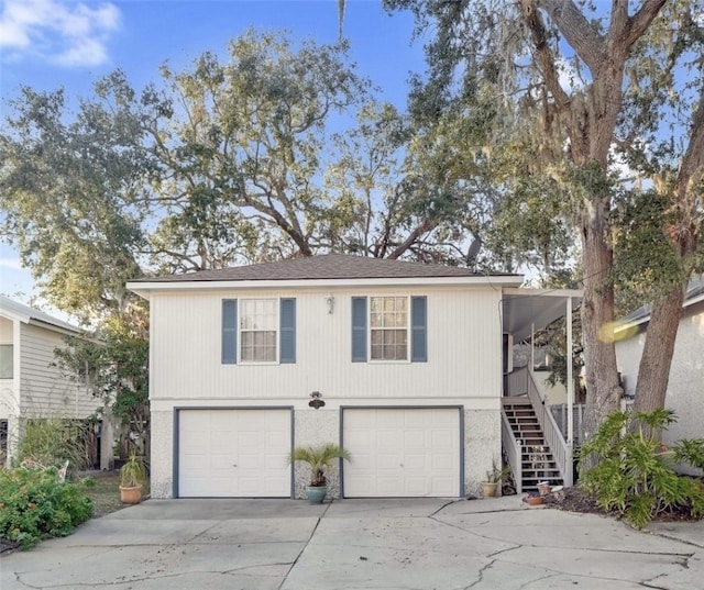 view of front of property featuring concrete driveway, an attached garage, and stairs