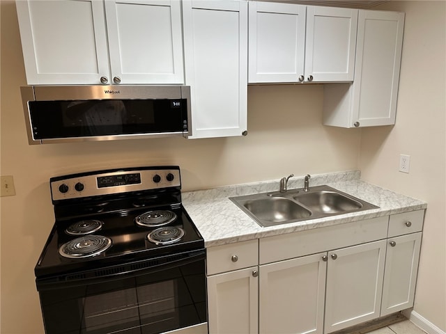 kitchen featuring light countertops, stainless steel microwave, white cabinets, a sink, and black range with electric cooktop