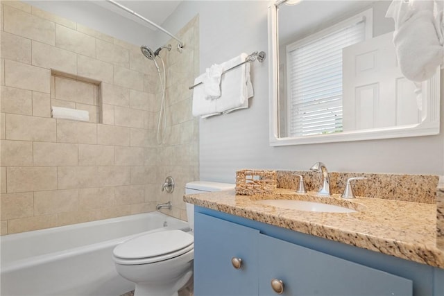 full bathroom featuring tiled shower / bath, vanity, and toilet