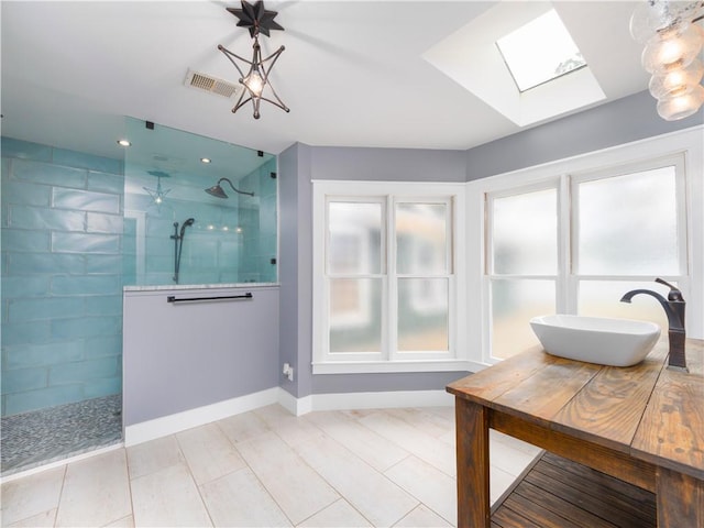 bathroom with sink, a tile shower, and a skylight