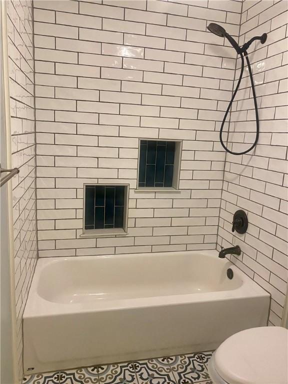 bathroom with toilet and tiled shower / bath