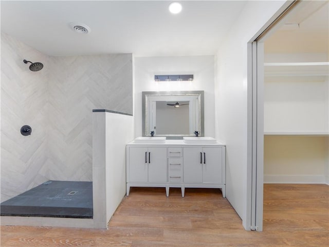 bathroom with wood-type flooring, vanity, and a tile shower