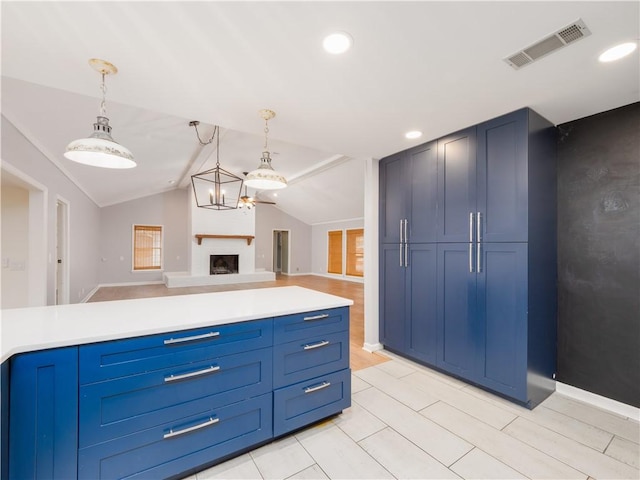 kitchen with hanging light fixtures, blue cabinetry, and vaulted ceiling