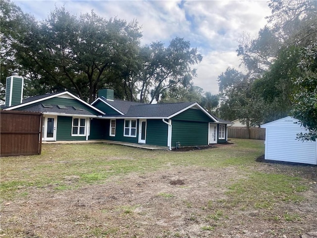 rear view of property featuring a storage shed and a lawn